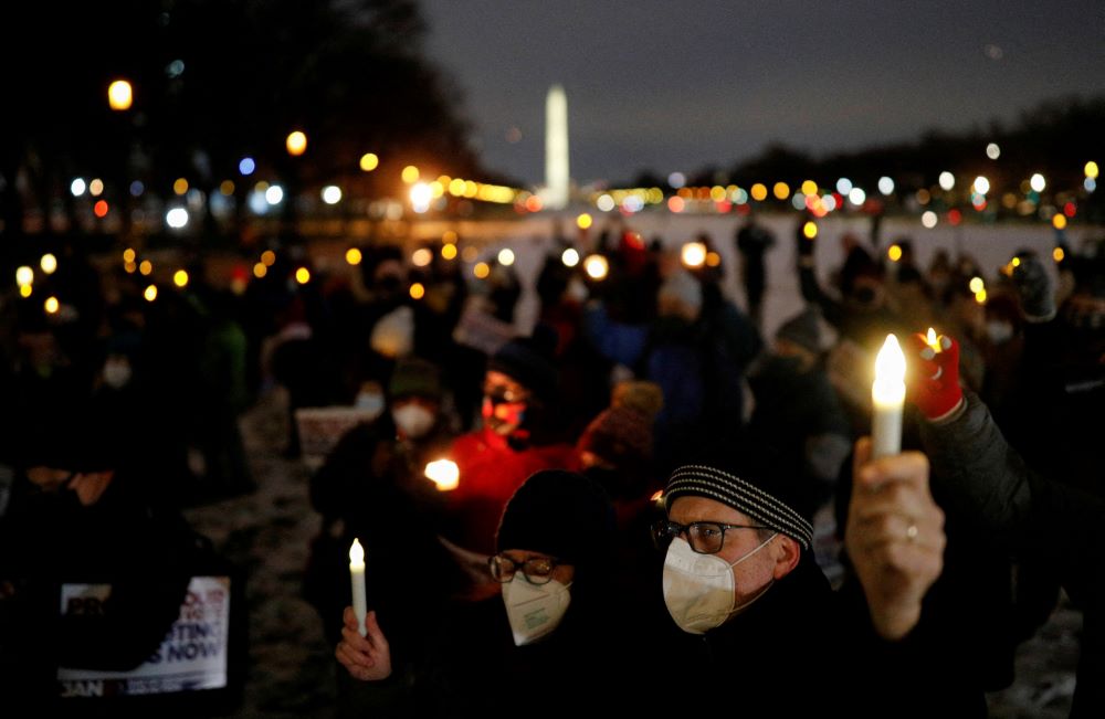 People hold up candles during a candlelight vigil on the National Mall in Washington, D.C., Jan. 6. It was the first anniversary of the attack on the Capitol by supporters of former President Donald Trump. (CNS/Reuters/Tom Brenner)