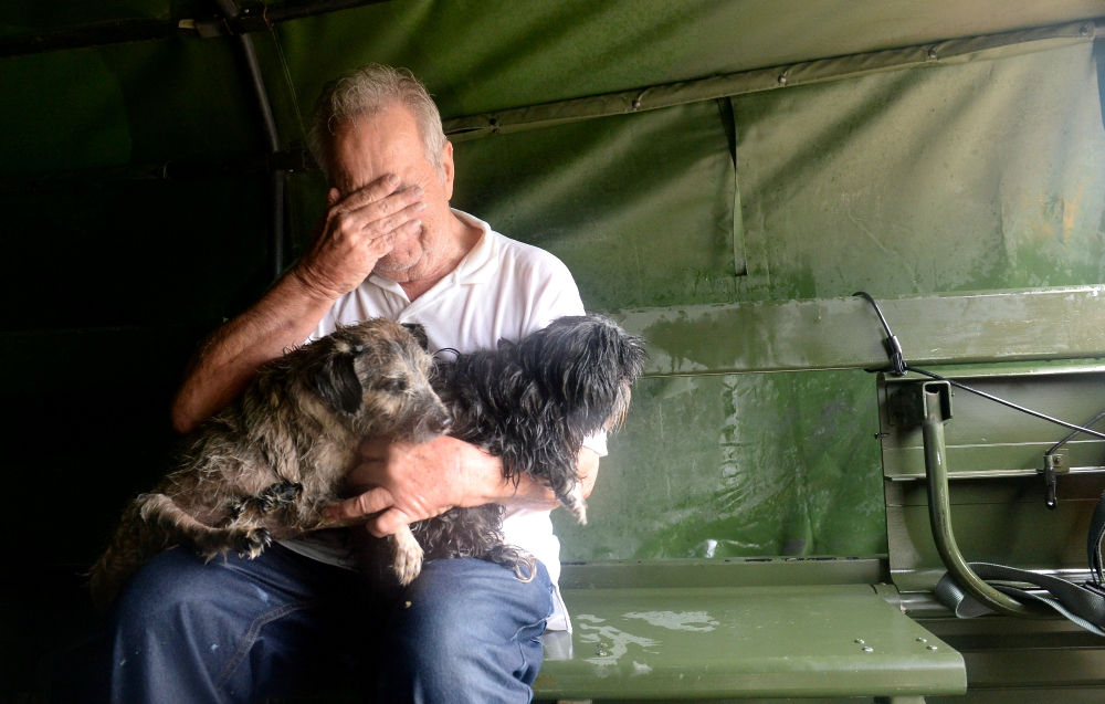 An evacuee holding two dogs becomes emotional after his Aug. 29 rescue by Texas National Guardsmen from severe flooding from Tropical Storm Harvey in Houston. (CNS/Army National Guard handout via Reuters/U.S. Army Capt. Martha Nigrelle)