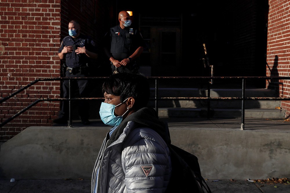 A woman walks past police officers in the Brooklyn borough of New York City Oct. 14, 2020. (CNS/Reuters/Shannon Stapleton)