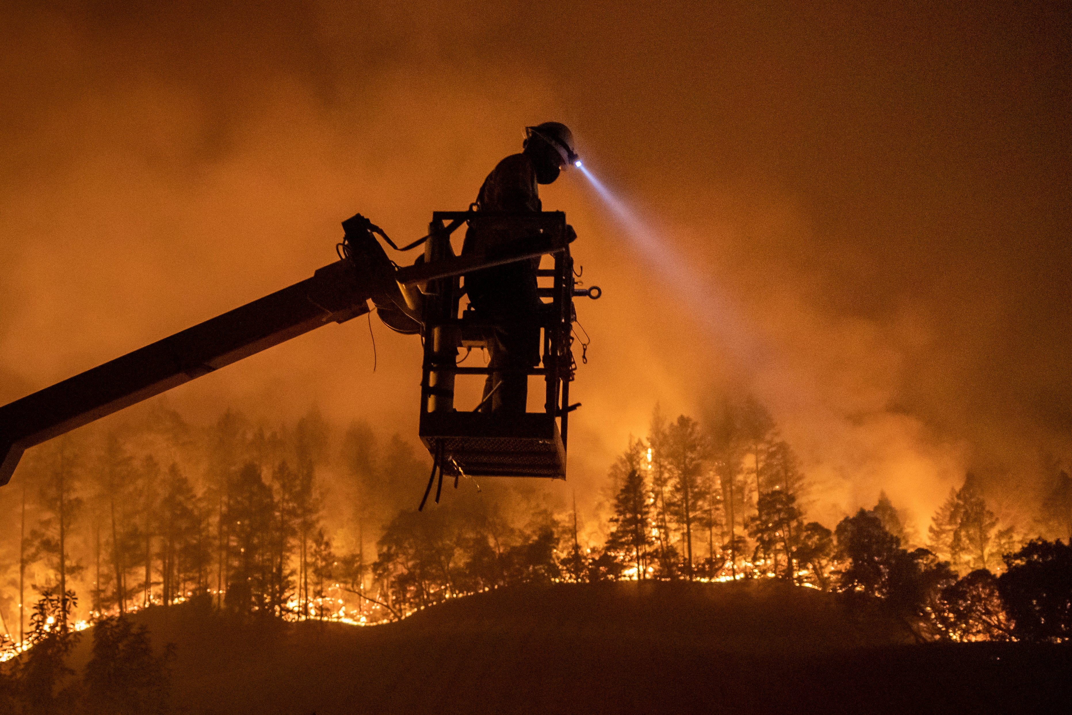 The Glass Fire burns in Calistoga, California, Sept. 28, as an employee of CableCom installs fiber optic cable. (CNS/Adrees Latif, Reuters)