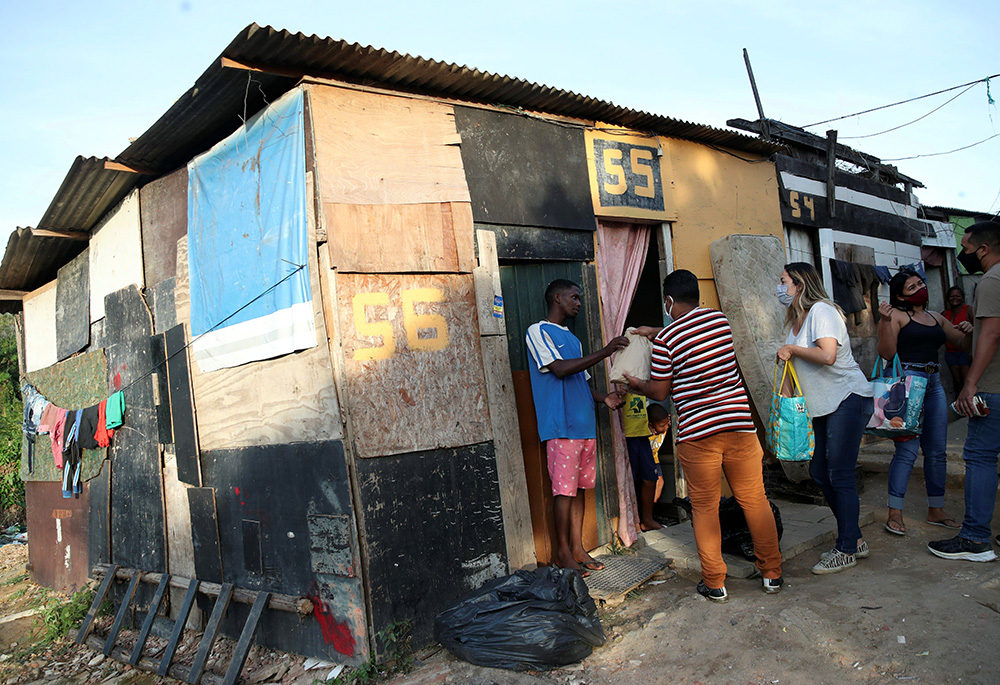 Residents in a poor section of Rio de Janeiro in Brazil receive food and bread produced at the Sanctuary of Our Lady of Fatima during the COVID-19 pandemic. Volunteers delivered the bread June 24, 2021. (CNS/Reuters/Ricardo Moraes)