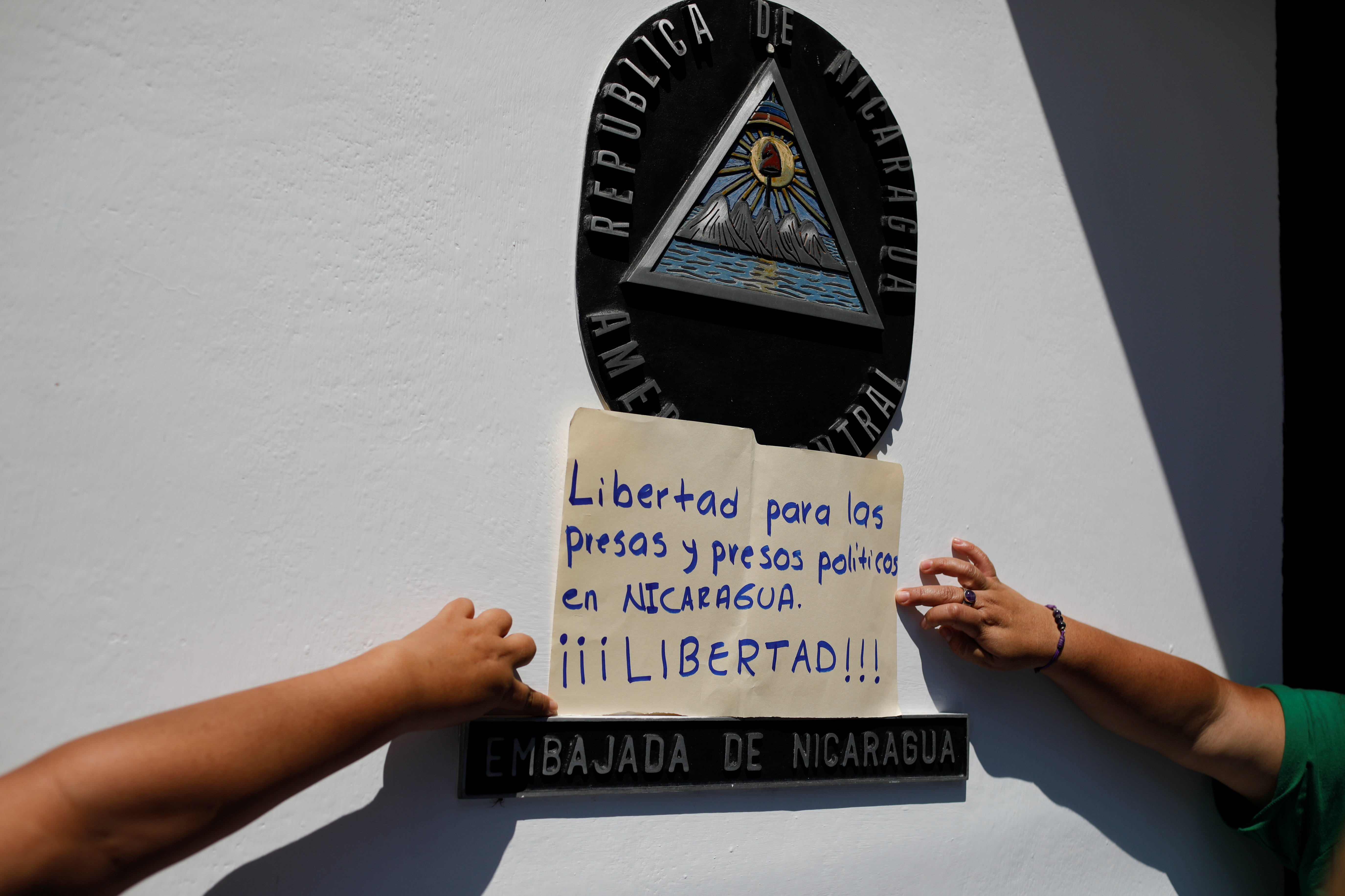 Women hold a poster that reads "Freedom to all political prisoners in Nicaragua, FREEDOM!" during a protest in front of the Nicaraguan embassy in San Salvador, El Salvador, June 30, 2021, to demand an end to repression and the release of political prisone