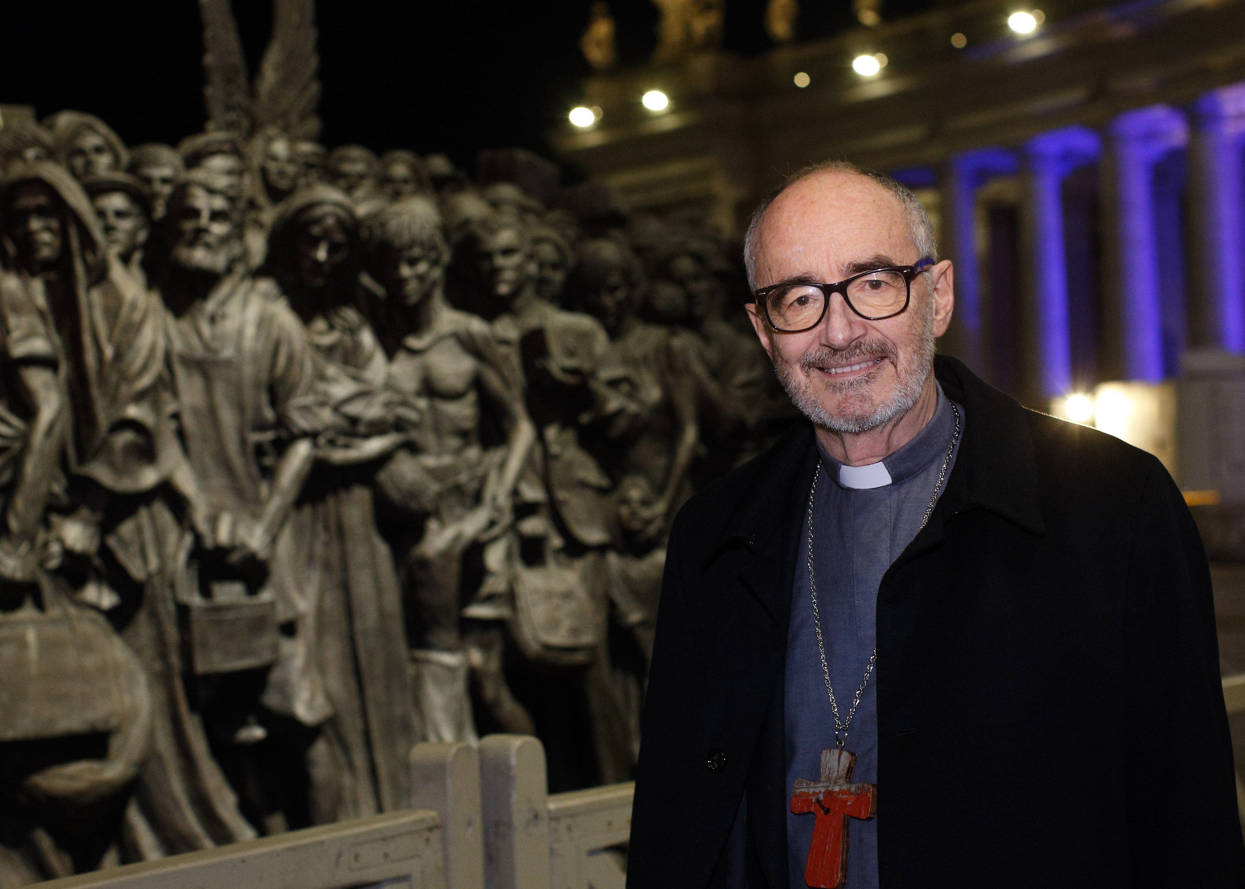 Canadian Cardinal Michael Czerny, undersecretary for migrants and refugees at the Vatican Dicastery for Promoting Integral Human Development, poses for a photo at the "Angels Unawares" statue in St. Peter's Square at the Vatican Dec. 15, 2020. In a virtua