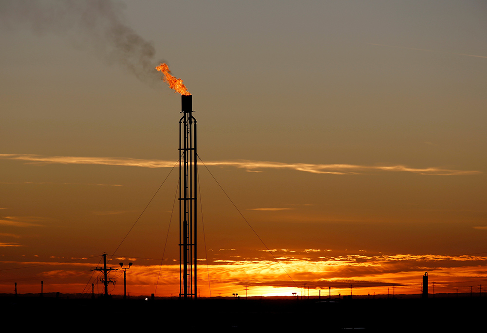 A flare burns excess natural gas in the Permian Basin in Loving County, Texas, in 2019. (CNS/Reuters/Angus Mordant)