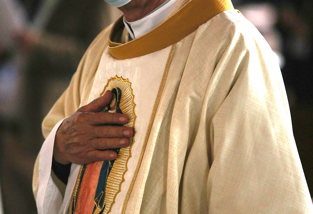 A clergyman touches an image of Our Lady of Guadalupe on his vestments during Mass Nov. 21, 2021, at the opening of the Nov. 21-28 Ecclesial Assembly of Latin America and the Caribbean, in Mexico City. (CNS/Emilio Espejel)