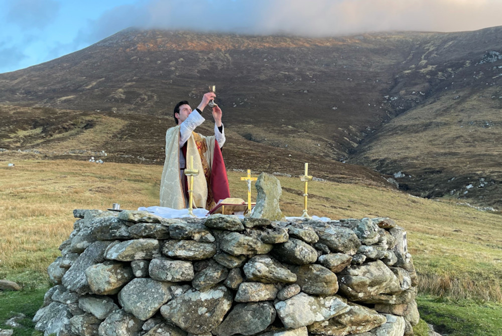 Fr. Gerard Quirke raises the chalice at Mass Rock overlooking Keem Bay on Ireland's Achill Island April 4, 2021. The church in Ireland is launching a Year for Vocations as it grapples with a steep decline in seminary numbers and with aging priests. (OSV News/Courtesy Irish Catholic/Seán Molloy)