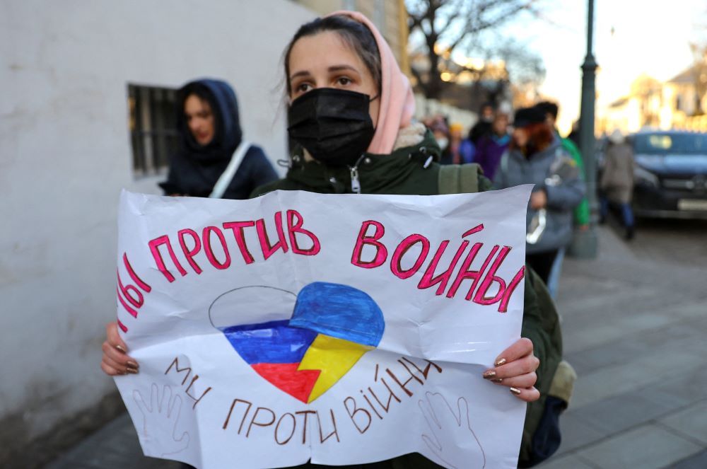 A young woman holds a sign that reads "We are against war."