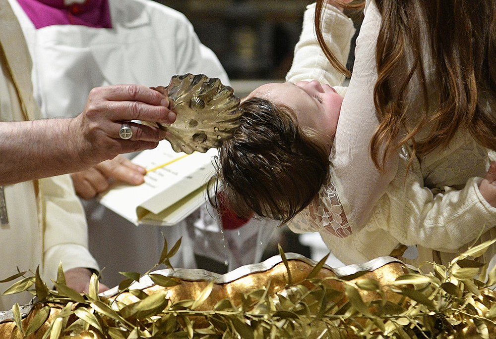 Pope Francis baptizes one of 13 babies during a Mass celebrating the feast of the Baptism of the Lord in the Sistine Chapel Jan. 8 at the Vatican. (CNS/Vatican Media)