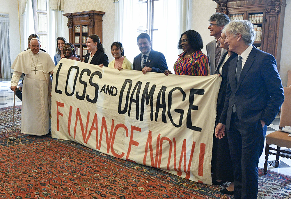 Pope Francis joins others in holding a banner during an audience June 5 at the Vatican, with the organizers of the Green & Blue Festival. The banner calls for financing a "loss and damage" fund that was agreed upon at the COP27 U.N. climate conference in 2022. The fund would seek to provide financial assistance to nations most vulnerable and impacted by the effects of climate change. (CNS/Vatican Media)