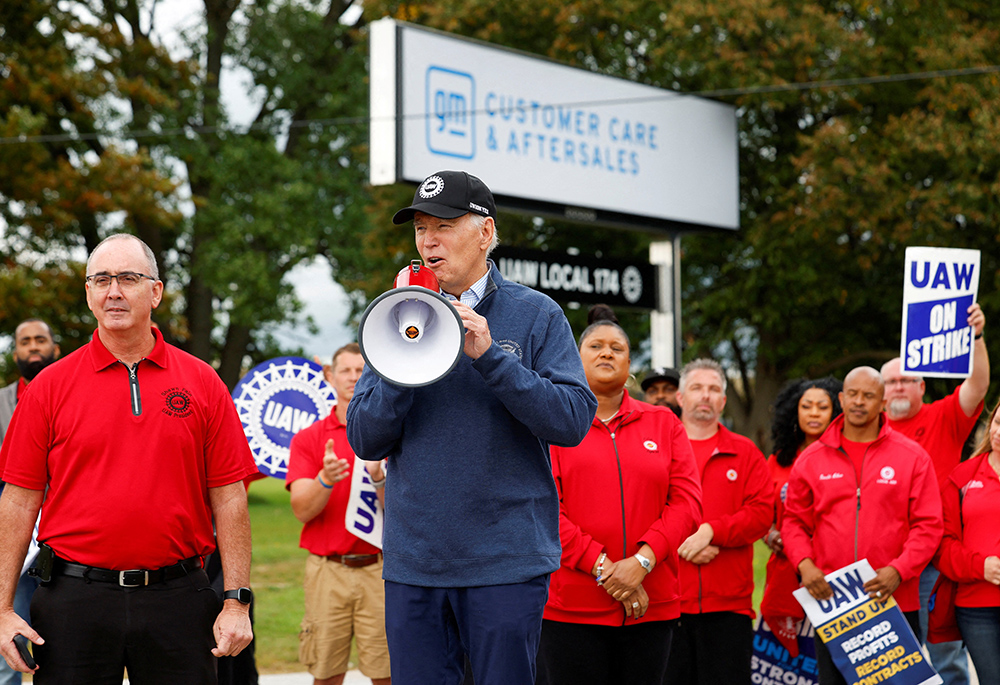 U.S. President Joe Biden speaks next to Shawn Fain, president of the United Auto Workers, as he joins striking UAW members on the picket line outside the GM's Willow Run Distribution Center in Belleville, Michigan, Sept. 26. Biden became the first known sitting U.S. president to join a labor strike. (OSV News/Reuters/Evelyn Hockstein)