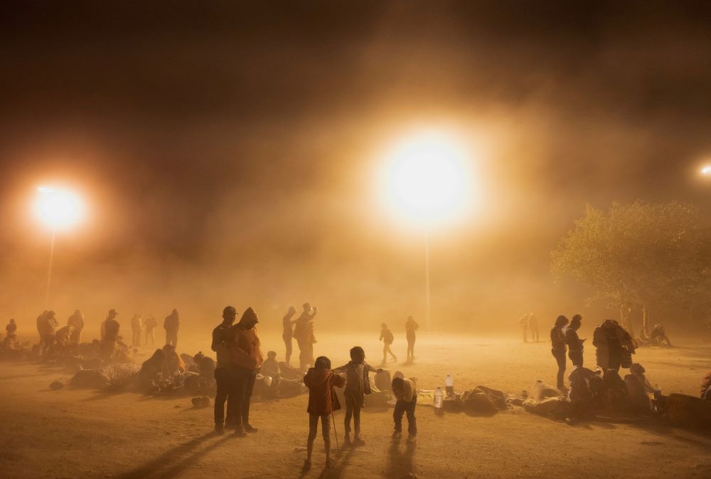 Migrants are battered by dust kicked up by high winds as they wait to be picked up by U.S. Customs and Border Protection officers near the U.S. border wall near El Paso, Texas, May 10.