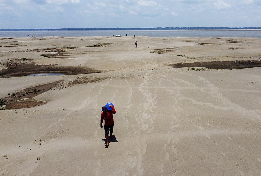 Residents of a riverside community carry food and containers of drinking water from an aid distribution due to the ongoing drought in Careiro da Varzea, Amazonas state, Brazil, Oct. 24, 2023. Earth last year shattered global annual heat records, numerous scientific bodies reported in early 2024. (AP/Edmar Barros, File)