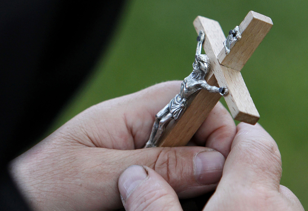 A woman holds a crucifix in this 2010 file photo. John Van Hagen's book Promise and Poison focuses attention on the traumatic impact of the Crucifixion on the first disciples and their followers,as well as the devastating effects of the destruction of the Temple a few decades later. (CNS/Reuters/Vasily Fedosenko)