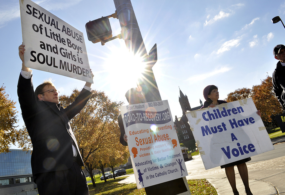 Protestors, from left, Richard Tollner, Fr. Bob Hoatson, Marianne Barone Trent, and Dick Regan demonstrate amid allegations that then-Syracuse assistant basketball coach Bernie Fine molested two former ball boys for years, on Nov. 21, 2011, in Syracuse, New York (Fine was later fired). Tollner is one of many abuse survivors who are suing the Diocese of Rockville Centre. (AP photo/Kevin Rivoli)