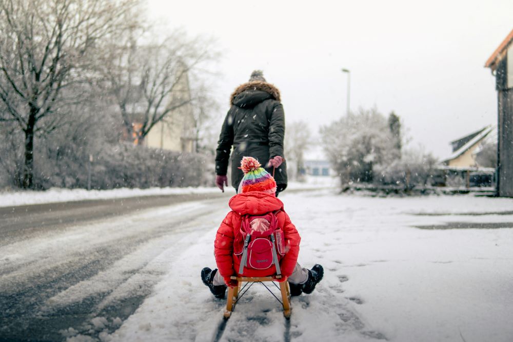 A person pulls another person on a sled. 