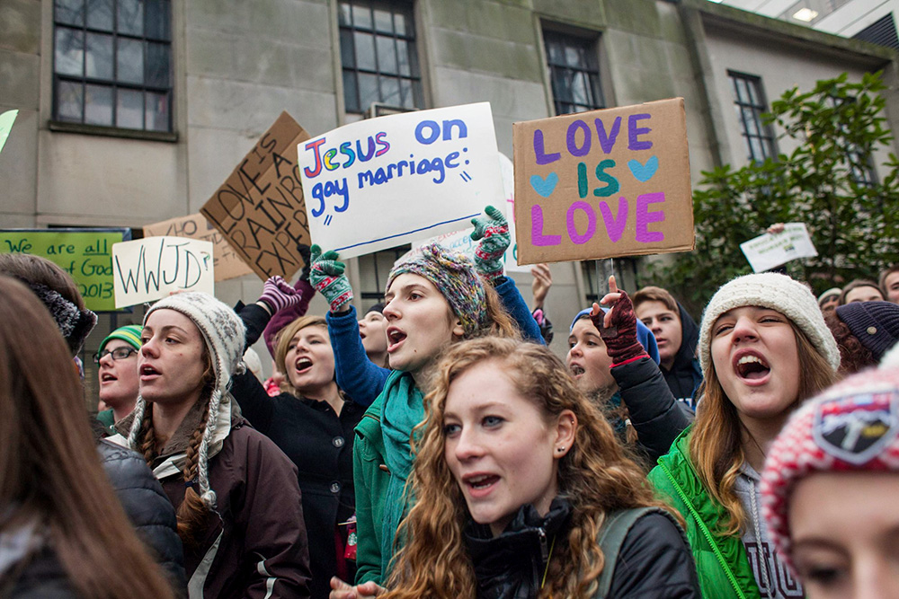 Eastside Catholic High School students display signs during a rally in support of the school's former vice principal, Mark Zmuda, outside the Seattle Archdiocese chancery building Dec. 20, 2013. Students rallied in Seattle after the Catholic high school asked Zmuda to resign because he married his same-sex partner. (CNS/Reuters/David Ryder)