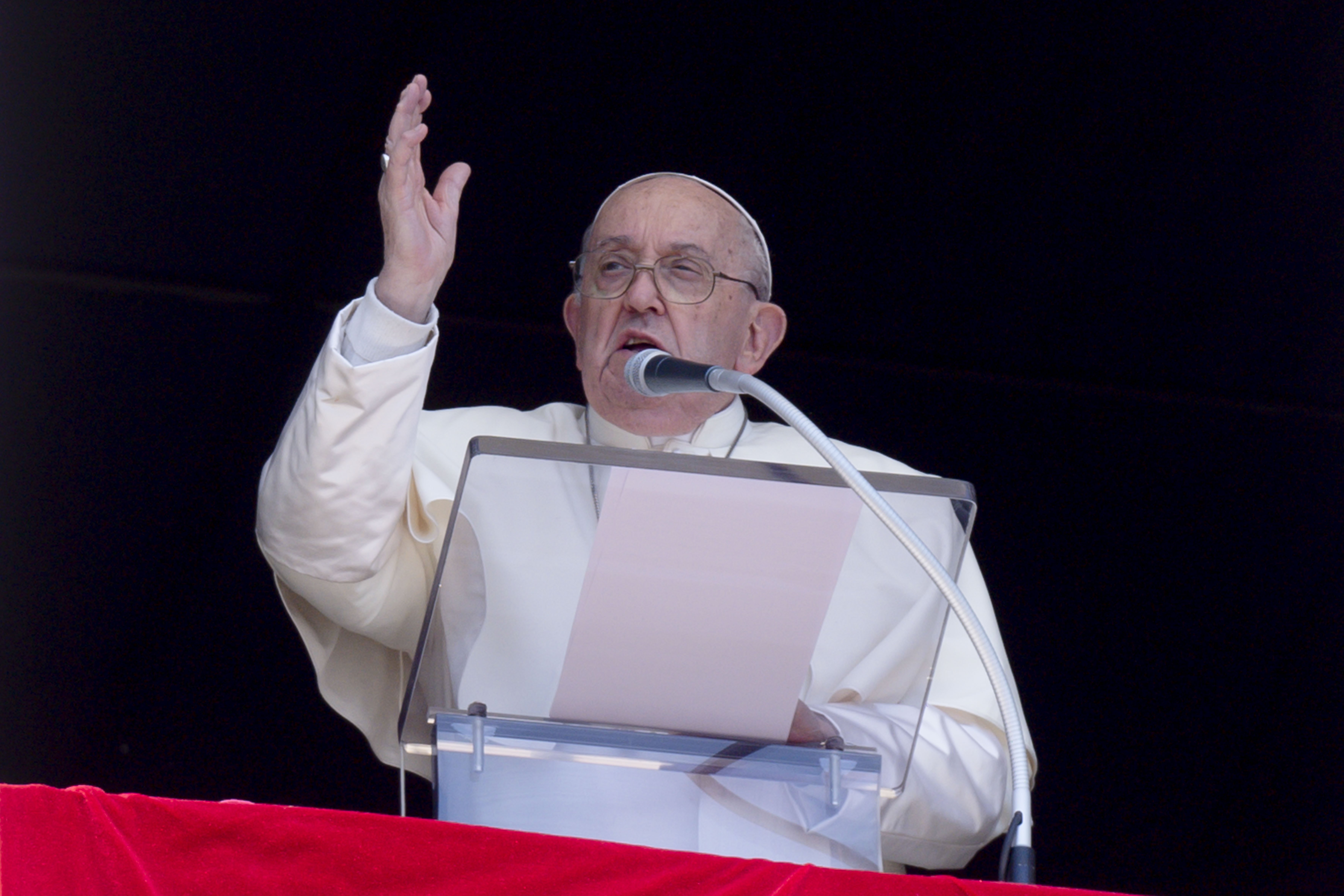 Pope Francis at lectern, above St. Peter's Square, hand raised in blessing. 