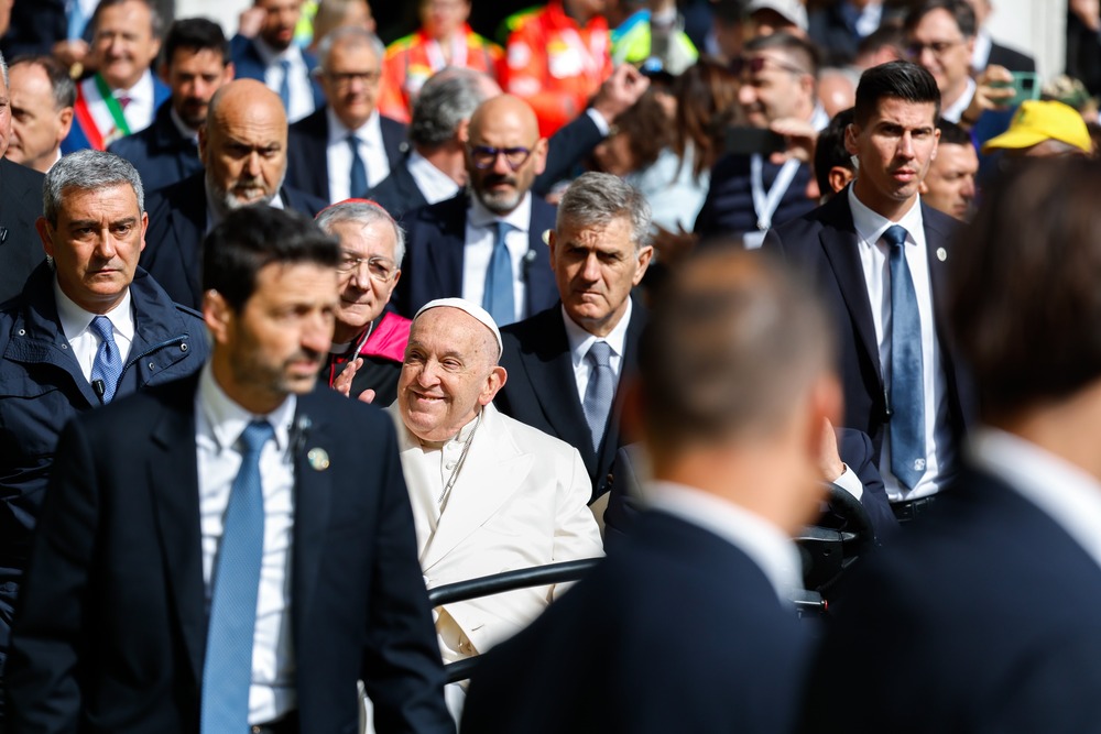 Pope Francis, framed by crowd, smiles in-focus