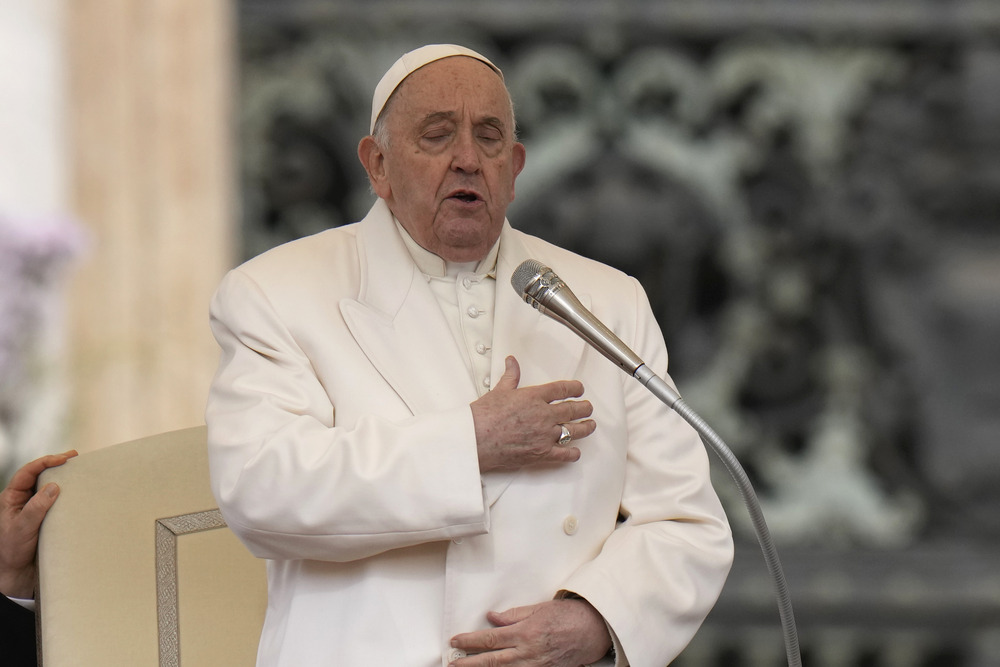 Pope Francis standing with hand to heart and eyes closed