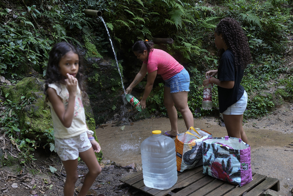 Young girl and family gather water from stream