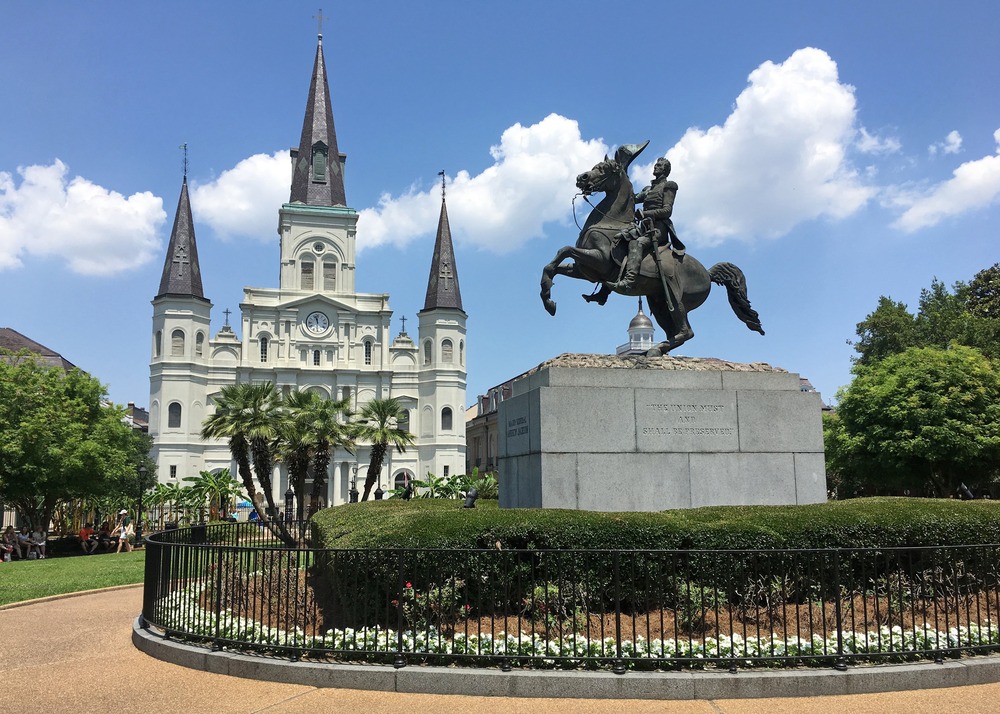 Towering Cathedral and equestrian bronze statue foregrounded against blue sky.