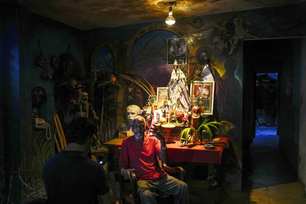 Man sits in front of altar in dim room