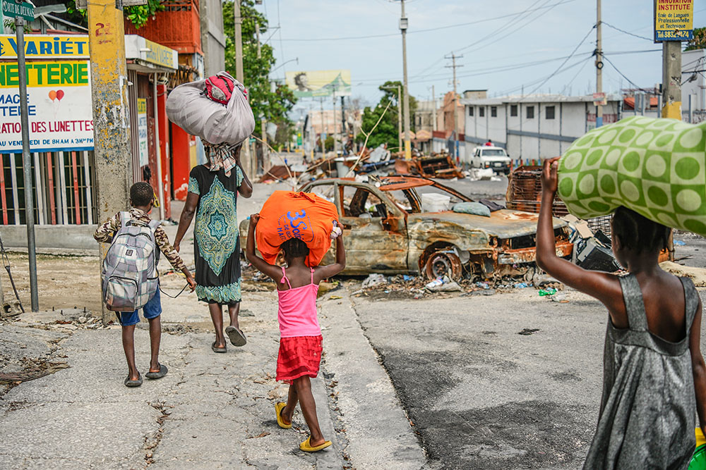 Residents walk past roadblocks as they evacuate the Delmas 22 neighborhood to escape gang violence in Port-au-Prince, Haiti, May 2. (AP/Ramon Espinosa)