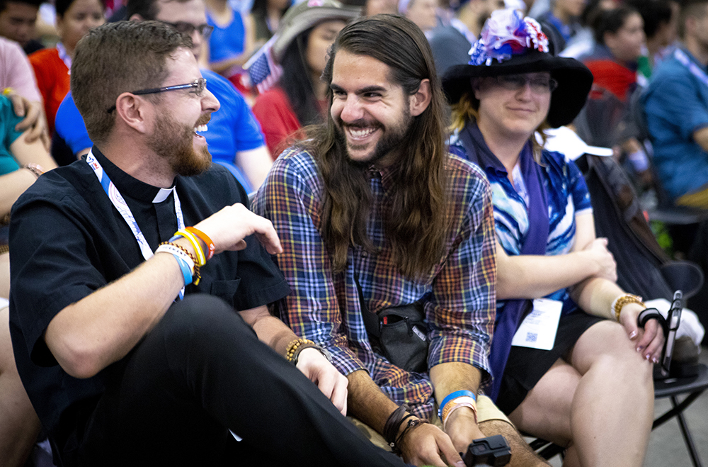 A young adult shares a laugh with a priest in Panama City Jan. 23, 2019, at FIAT, the largest English-language World Youth Day event. Musical performances and testimonials were mixed with frank discussion about the clergy sexual abuse scandal. (CNS/Chaz Muth) 