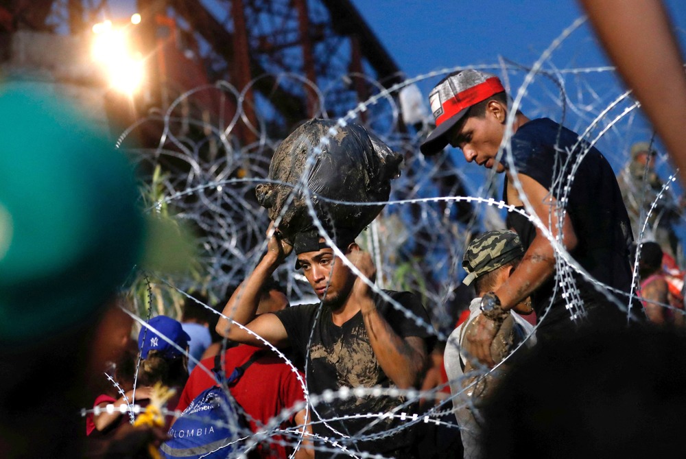 Young men framed by coils of barbed fencing. 