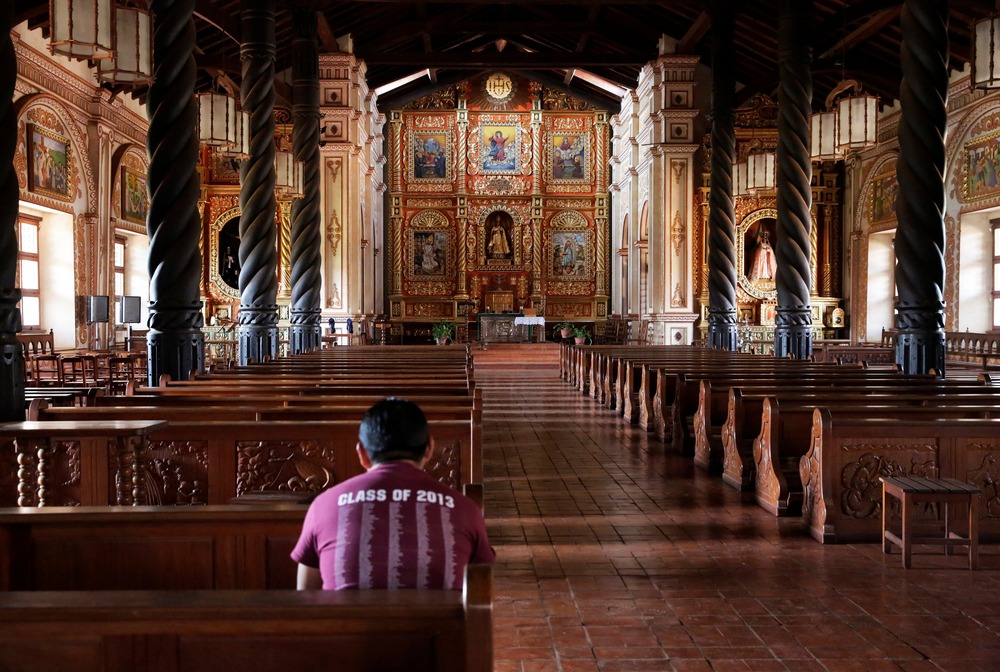 Ornate sanctuary pictured, with man in pew. 