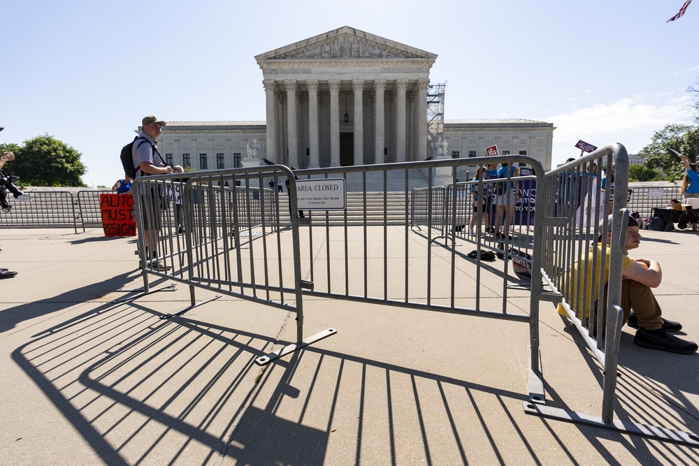 People sit and stand in front of large courthouse building