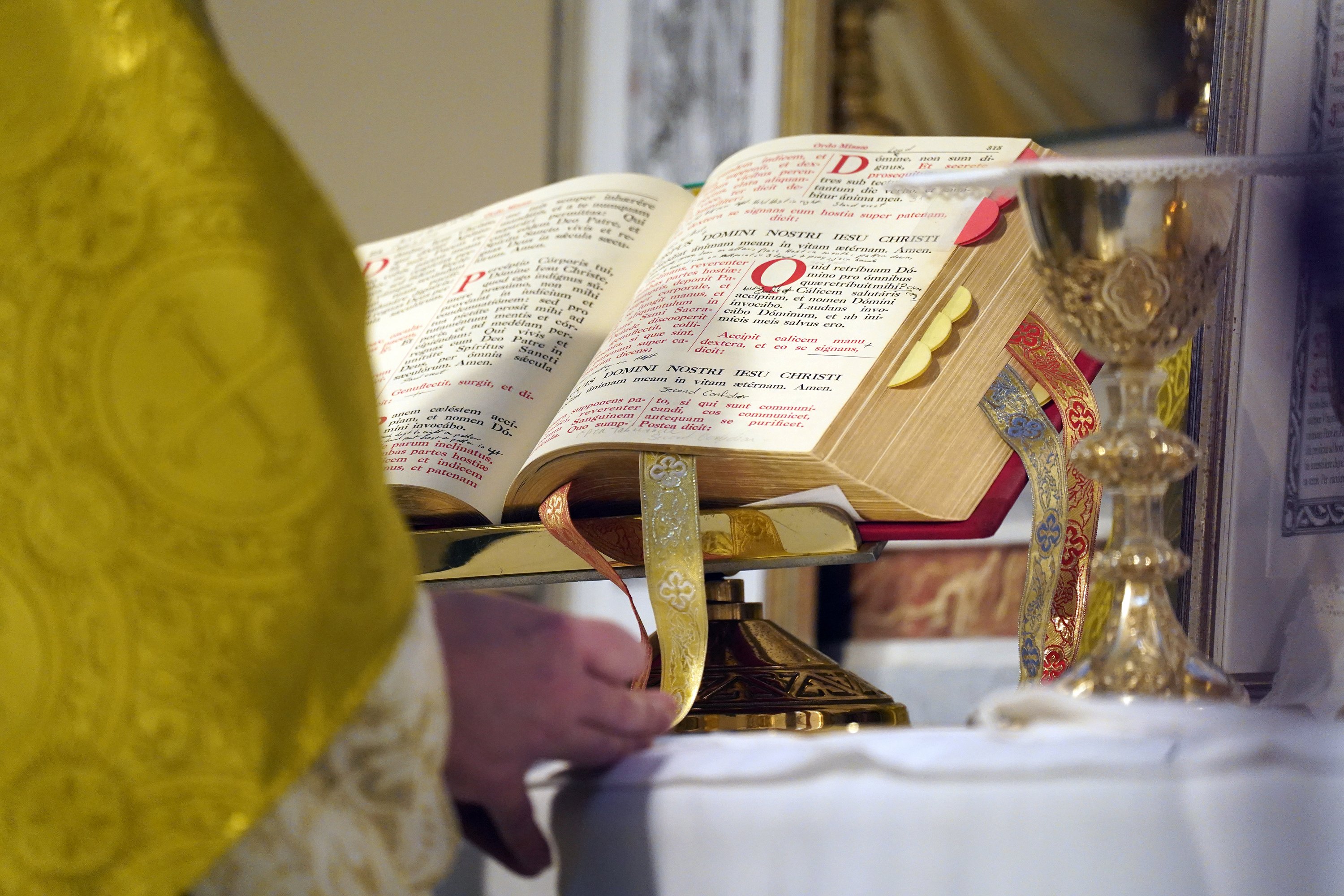 Altar shown up close, as well as priest's hands and vestments. 