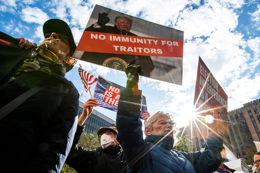 Protesters hold signs against presidential immunity