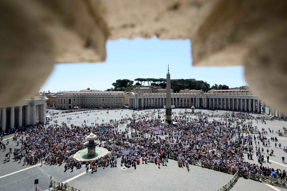 Crowd in square framed by stone outlook. 