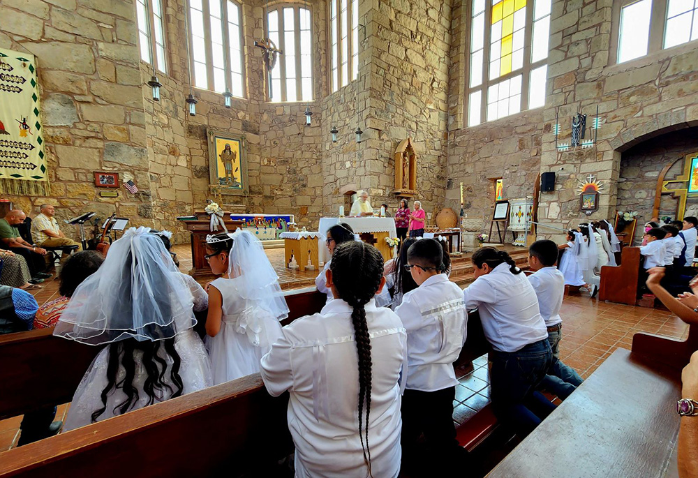 Fr. Dave Mercer, then-pastor of St. Joseph Apache Mission in Mescalero, New Mexico, stands at the altar during a first Communion Mass. Franciscan Br. Robert Lentz's icon "Apache Christ" adorns the wall behind Mercer. (Courtesy of Dave Mercer)