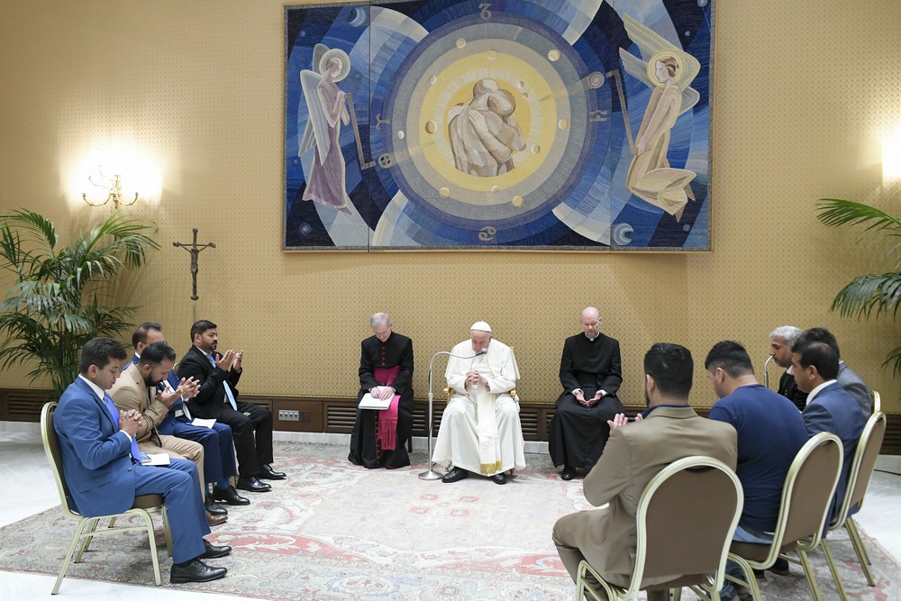 Francis seated, flanked by prelates, seated in circle around pope are association representatives. 