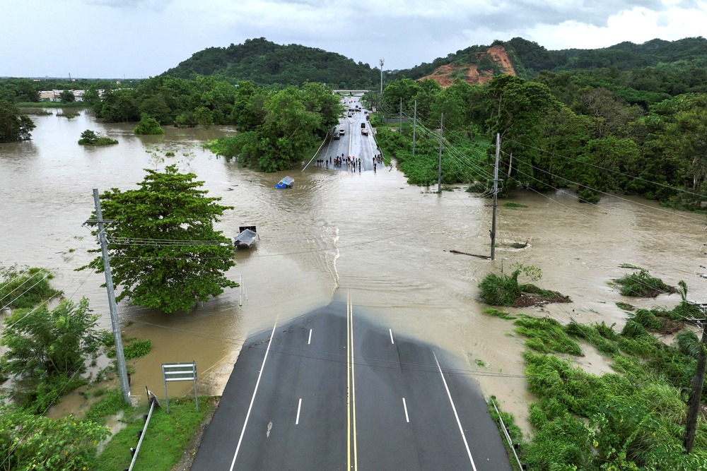 Aerial view of water completely covering middle of paved bridge. 