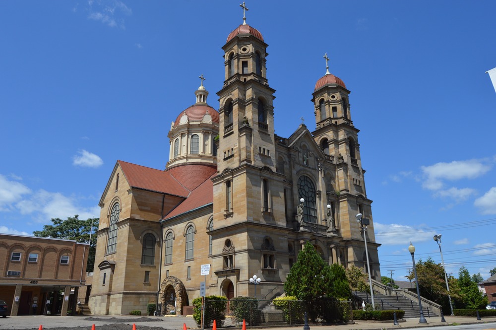 Large, stone Church building pictured from below, looming against bright blue sky. 