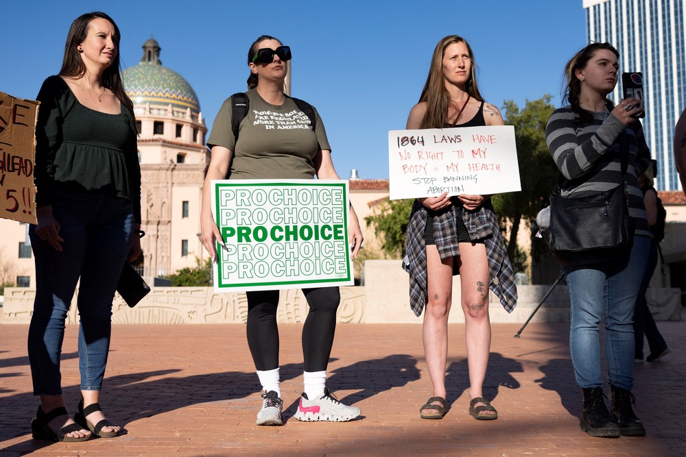 Four women stand holding signs. 