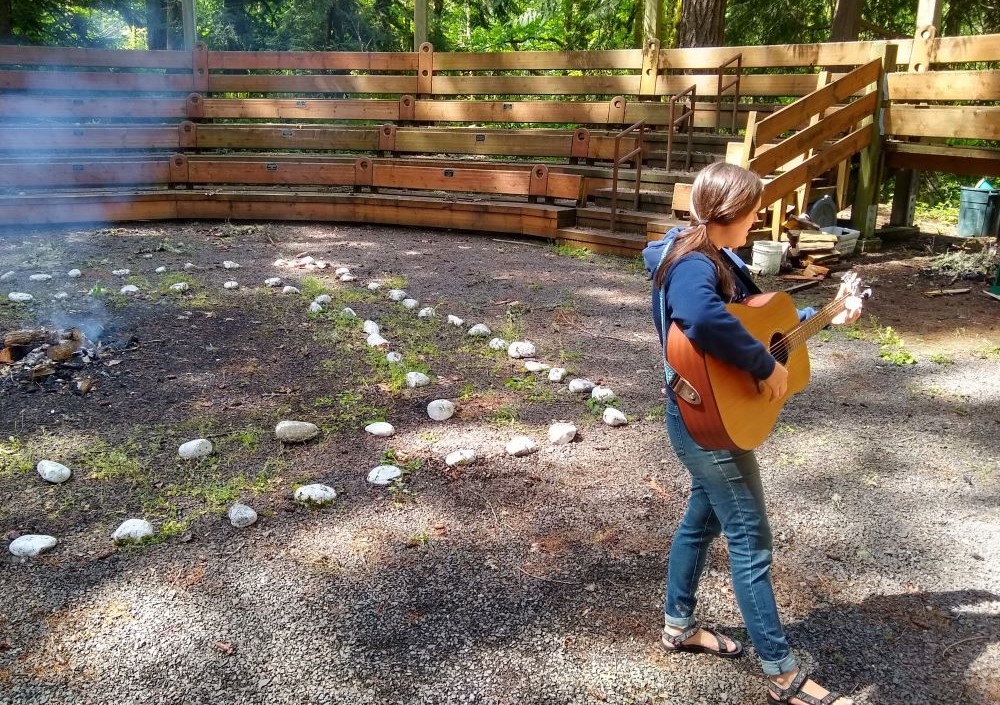 Sr. Terri Schell plays guitar around a campfire. 