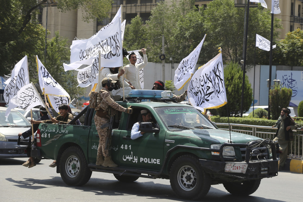 Soldiers ride in truck holding flags. 