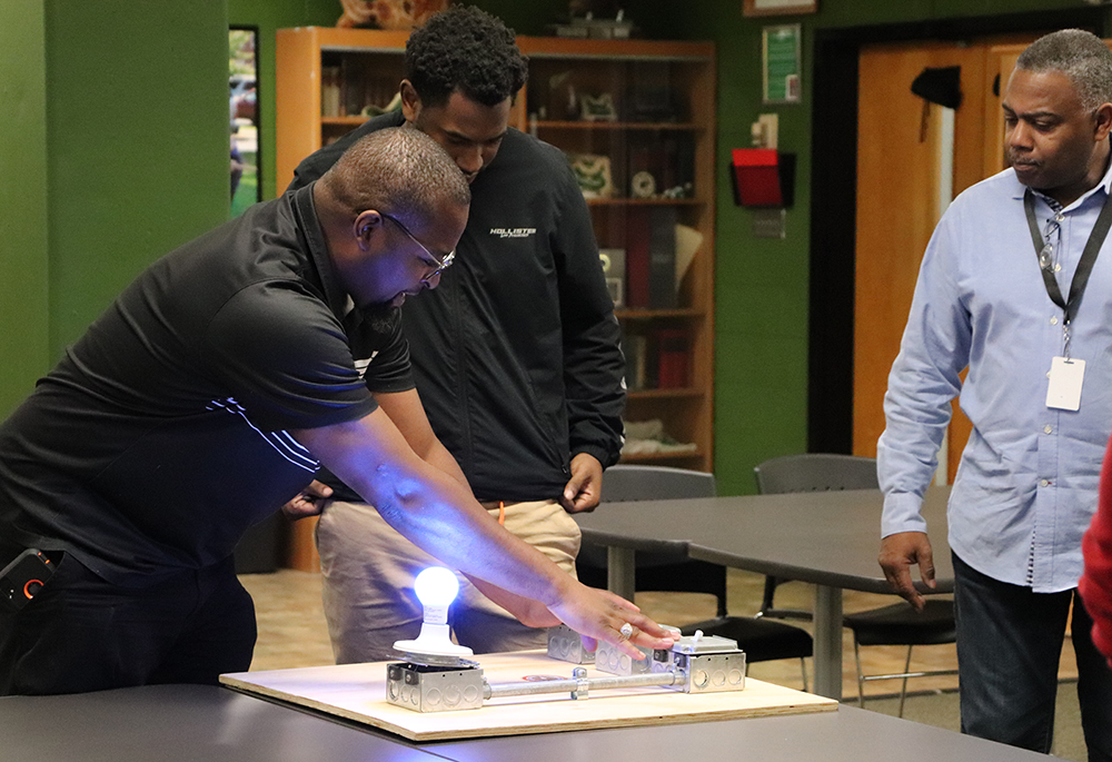 Kelly Stokes, far left, an instructor with Electricians Local 1 in St. Louis, works with student Roderick Brown from St. Mary's South Side Catholic High School in St. Louis, while Tracy Hykes, a pre-apprentice instructor, at right, looks on. (Courtesy of St. Mary's South Side Catholic High School)