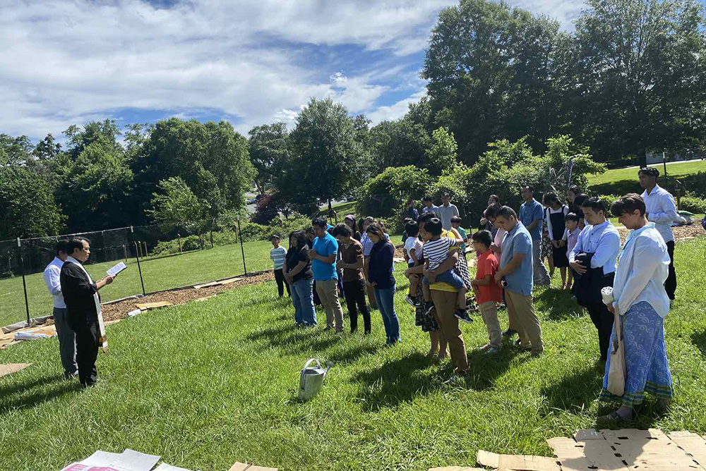 Fr. Paul HtunKhine blesses a community garden begun by Our Lady of Victory parishioners in Baltimore this summer. The garden's aim is to provide for the campus’ busy food pantry. (Courtesy of Joan Huai)