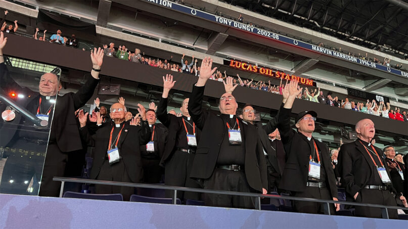 Bishops wearing plain black clerics stand with hands raised. 