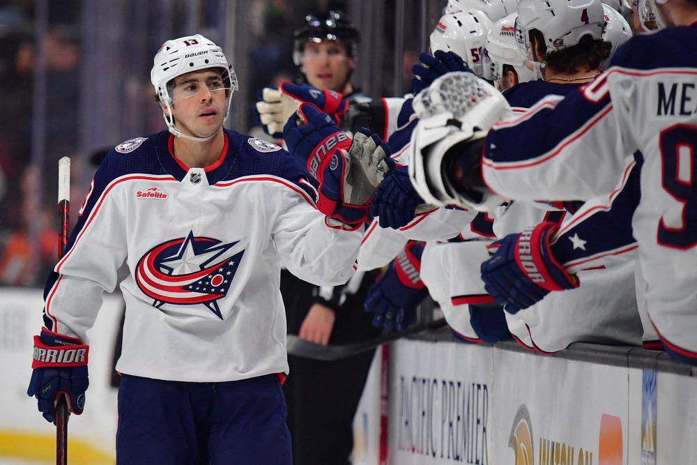 Gaudreau skates past teammates in stands, slapping their hands.