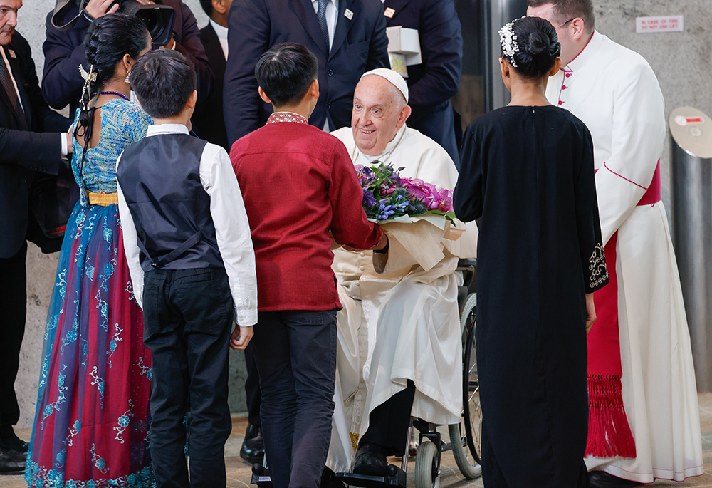 Pope Francis receives a bouquet of flowers from a group of children as he arrives Sept. 11 in Singapore, the last stop on his four-nation visit to Asia and the Pacific. (CNS/Lola Gomez)