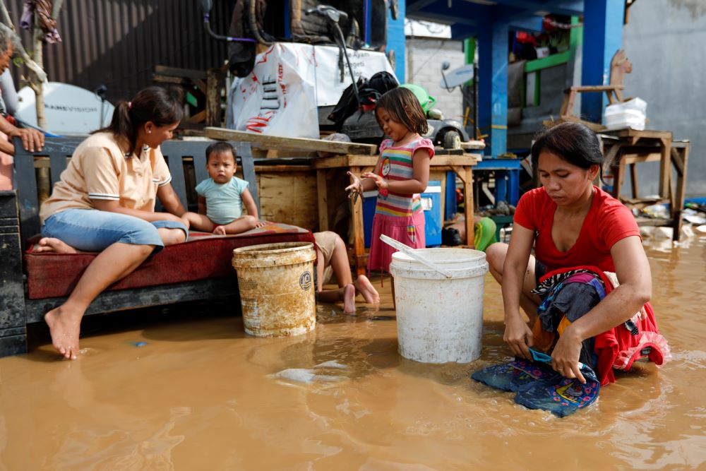 A woman washes clothing in a flooded street.