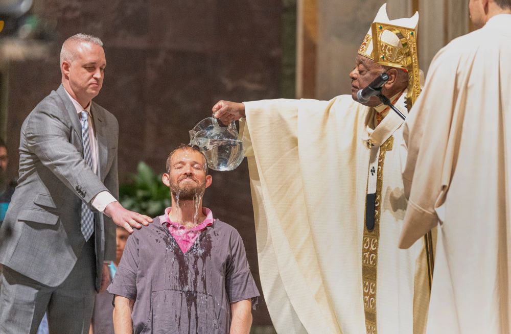 Washington Cardinal Wilton Gregory baptizes Andre Gouyet during the Easter Vigil April 8, 2023, at the Cathedral of St. Matthew the Apostle in Washington.