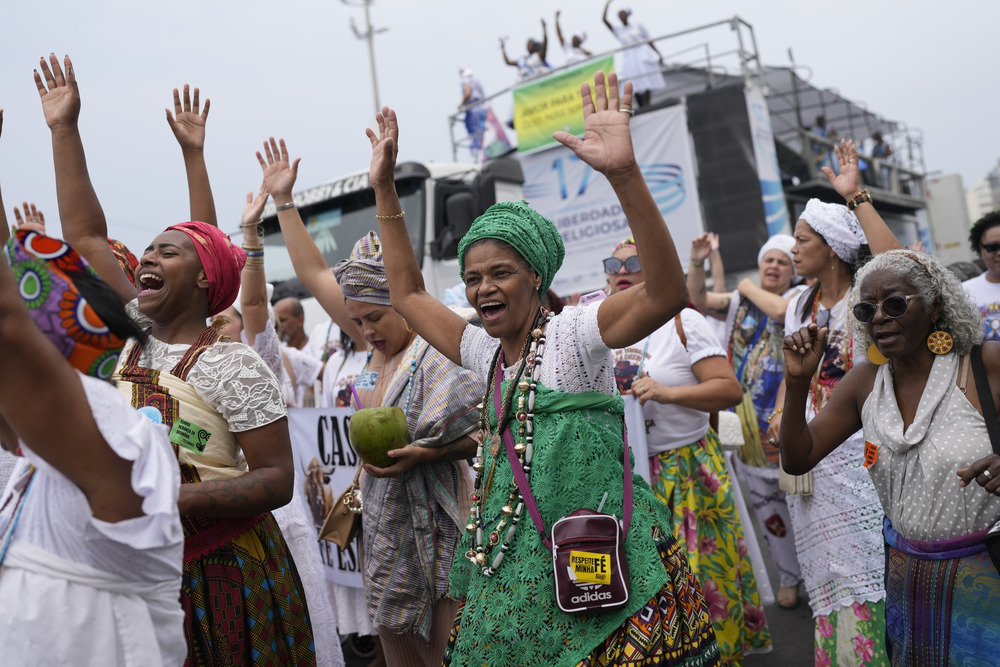 Colorfully garbed women cheer and dance in procession. 