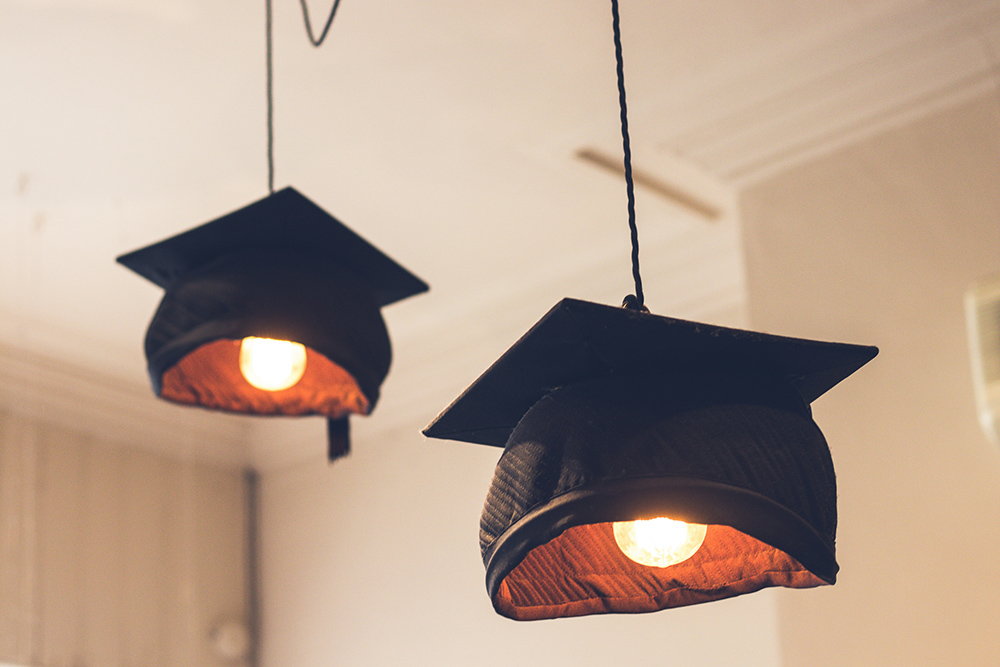 Graduation caps hanging as lights (Unsplash/Suad Kamardeen)